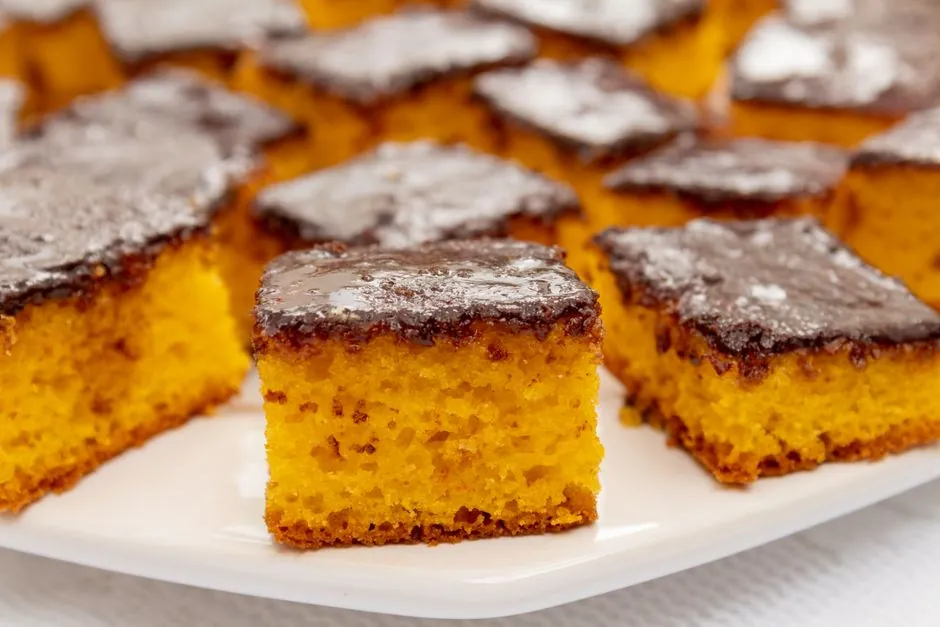 Close-up of moist carrot cake squares with chocolate glaze on a white plate.