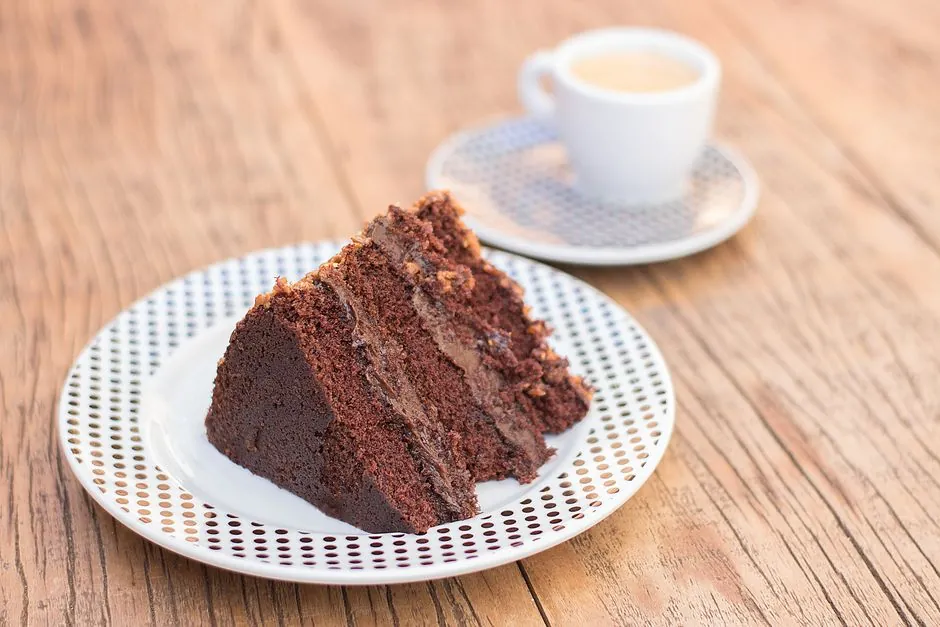 Delicious slice of chocolate cake served with coffee on a rustic wooden table, perfect for dessert lovers.