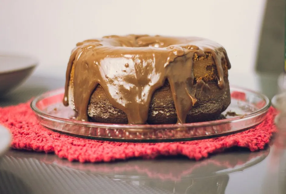 Rich chocolate bundt cake drizzled with cocoa glaze, presented on a glass plate.