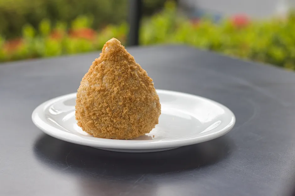 Close-up of a Brazilian coxinha on a plate, showcasing its golden, crispy exterior.
