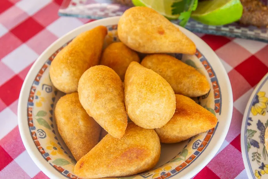 Plate of golden Brazilian coxinhas on a checkered tablecloth. Perfect for snacks or appetizers.