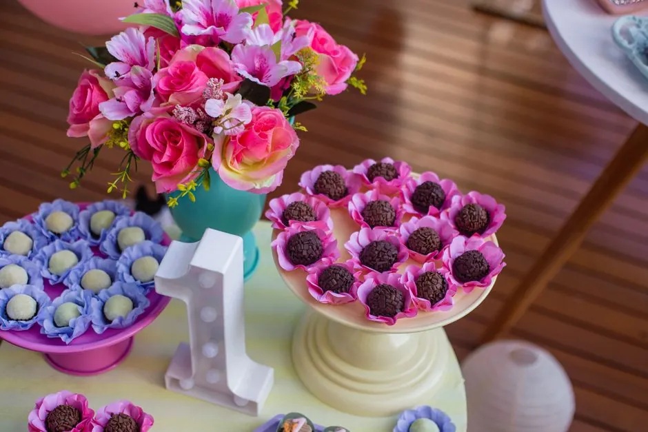 Colorful display of chocolates and candies on cake stands with floral decor for a birthday party.
