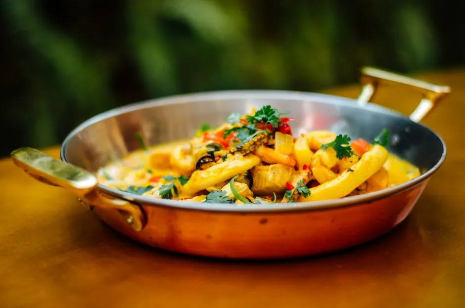 Delicious seafood pasta served in a copper pan, showcasing vibrant ingredients and colorful presentation.