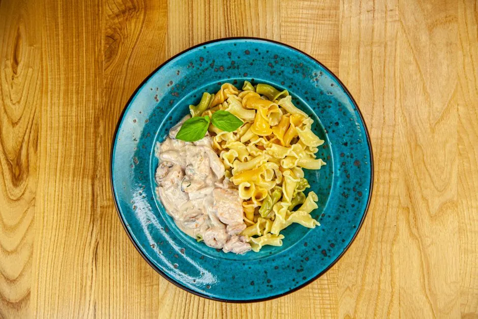 Appetizing creamy pasta on a rustic blue plate, perfect for dinner.
