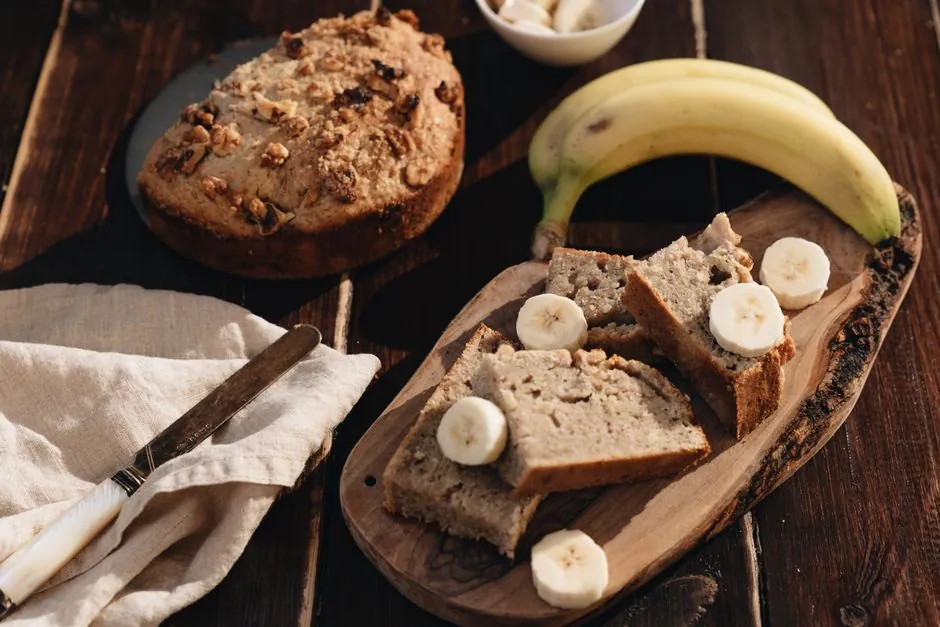 A rustic presentation of homemade banana bread with fresh bananas on a wooden board.