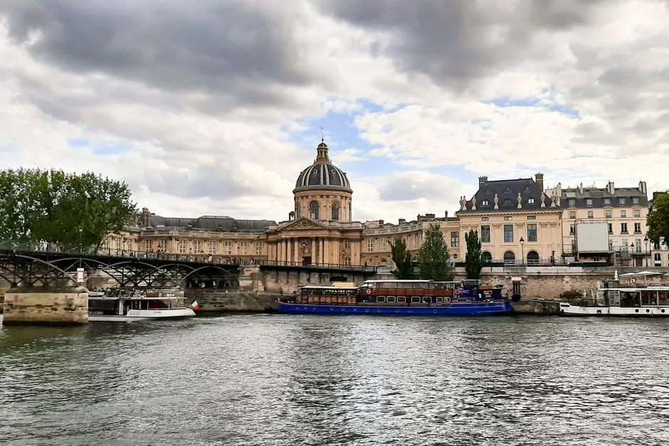 Scenic view of iconic Paris architecture along the Seine River on a cloudy day.