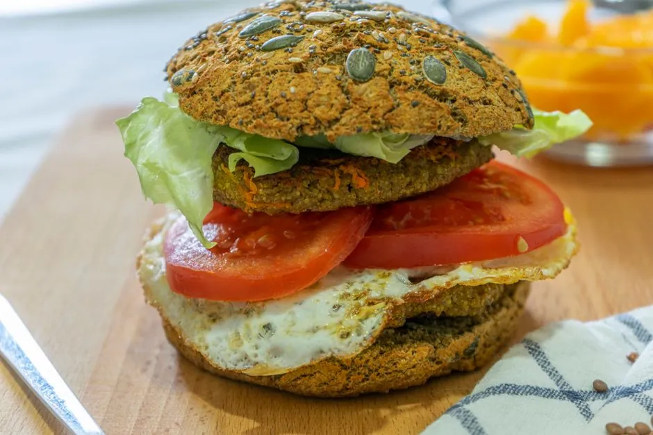 Close-up of a delicious vegan burger with fresh lettuce and tomato on a seeded bun, perfect for a healthy meal.