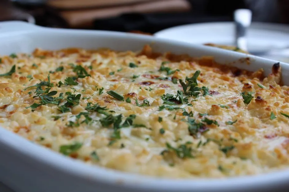 Close-up of a golden baked casserole dish topped with herbs, perfect for a comforting meal.