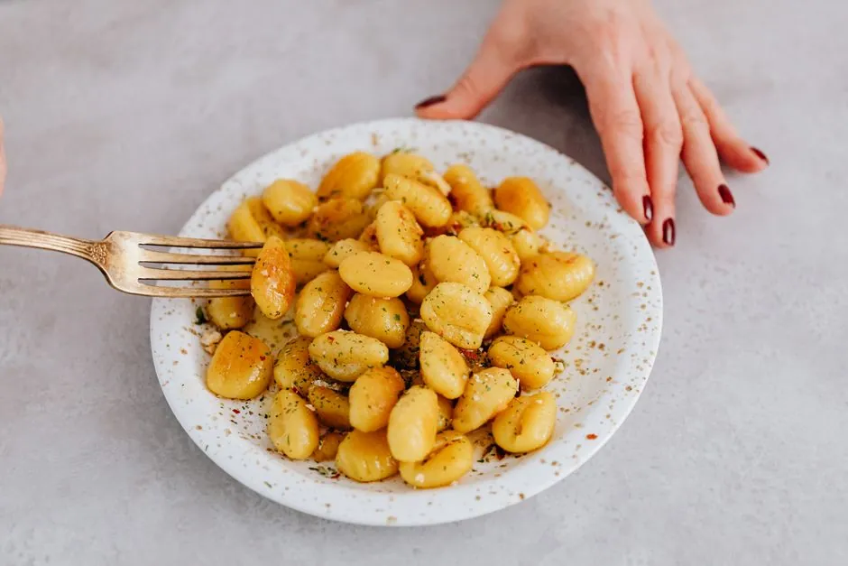 Freshly prepared gnocchi served on a ceramic plate with a fork. Perfect for Italian food lovers.