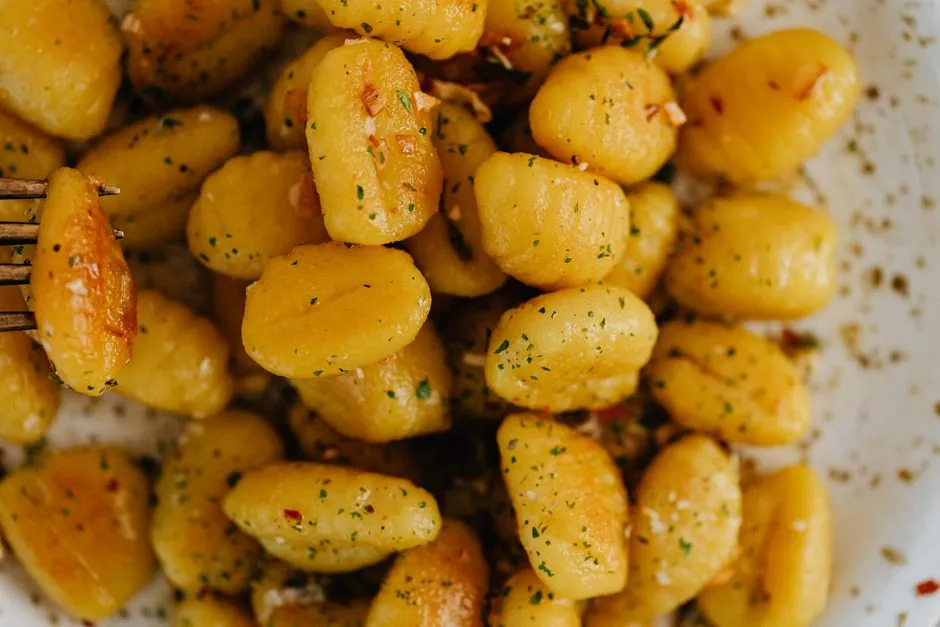 A savory plate of golden gnocchi garnished with herbs, showcasing Italian culinary artistry.
