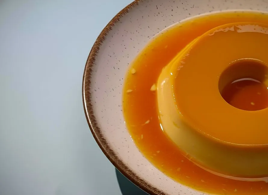 Delicious creamy caramel flan served on a ceramic plate with smooth texture in a gentle soft light.