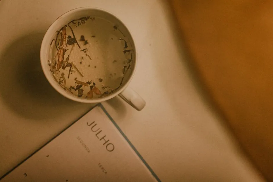 Overhead view of herbal tea in a cup next to a July calendar page, creating a warm and cozy ambiance.