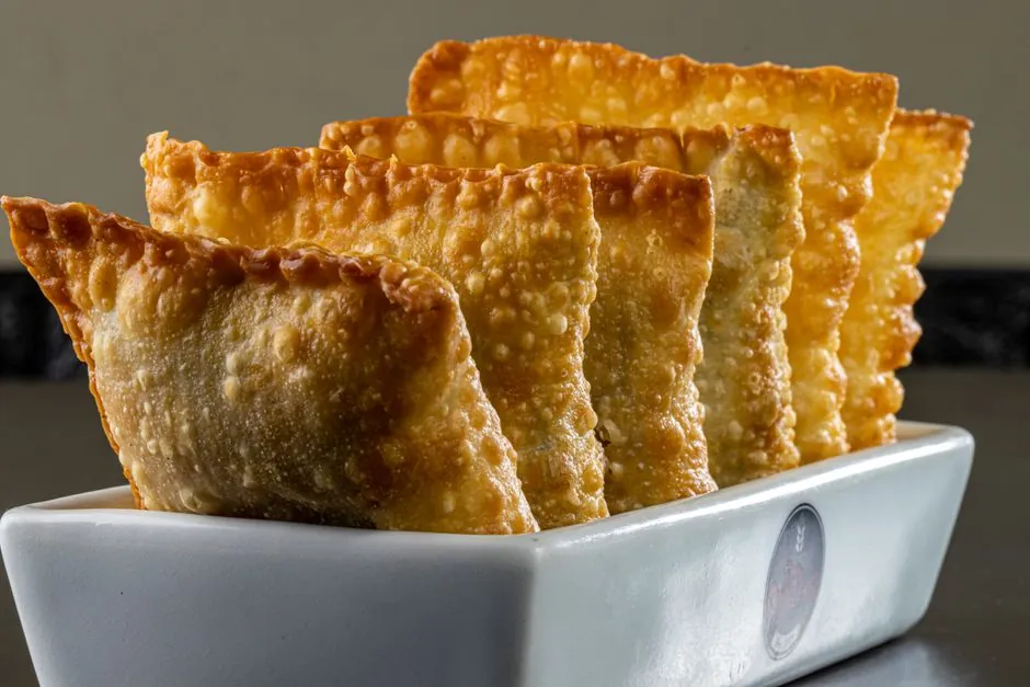 Golden brown Brazilian pastéis served in a white ceramic dish, perfect for food lovers.