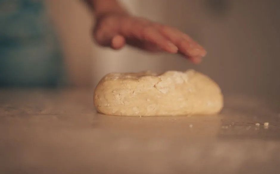Hand kneading dough on a kitchen counter, focusing on texture and art of baking.