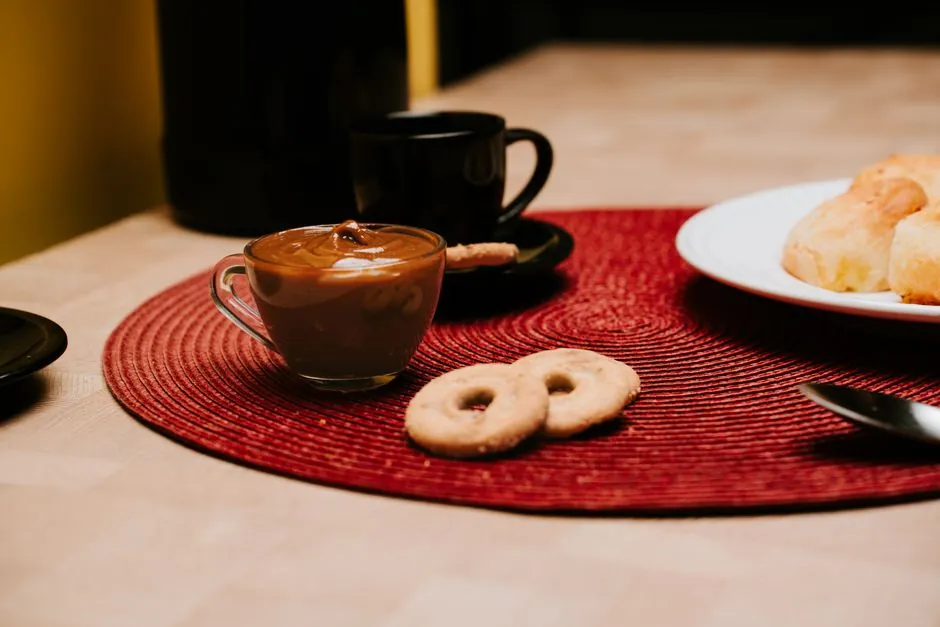 A warm breakfast setting featuring coffee, pastries, and cookies on a red placemat.