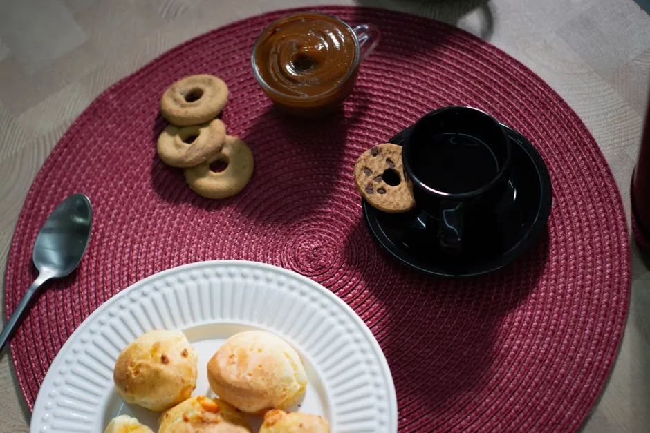 Enjoy a cozy afternoon snack with Brazilian cheese bread, black coffee, and dulce de leche in São Paulo.