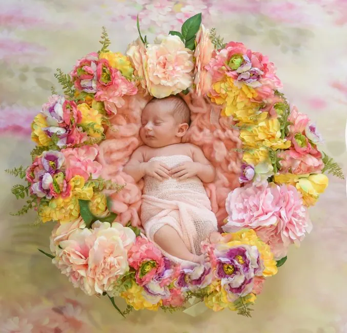 Peaceful newborn baby nestled in a vibrant floral arrangement, exuding innocence and beauty.