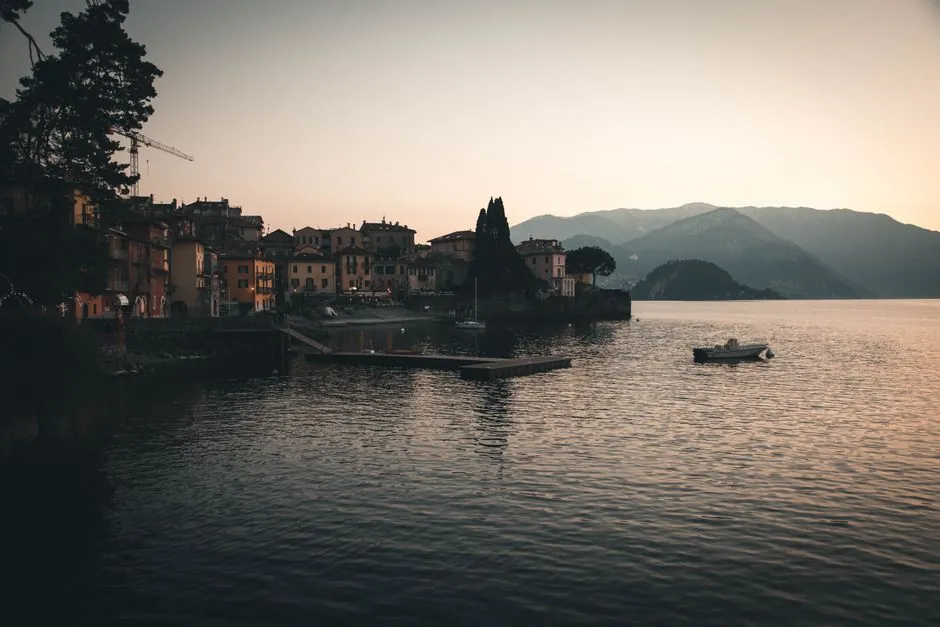 Serene evening landscape of Lake Como with boats and a picturesque village.