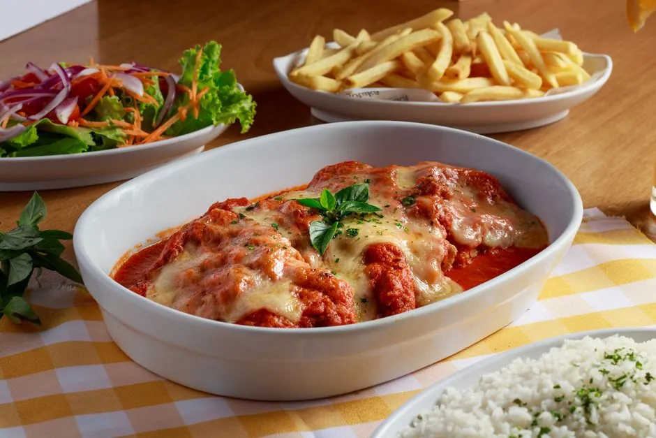 Delicious cheesy lasagna served with fries and a fresh salad, perfect for a hearty meal.