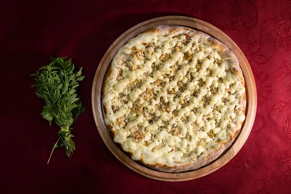 Top-down view of a cheese-loaded Italian pizza with fresh herbs on a wooden platter, perfect for gourmet lovers.