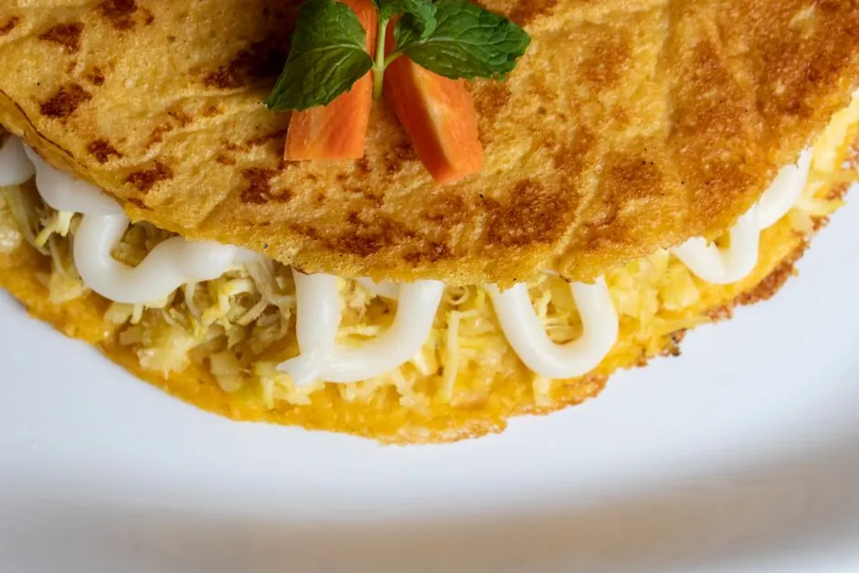 A delectable cheese-filled omelette garnished with fresh mint and carrot slices.