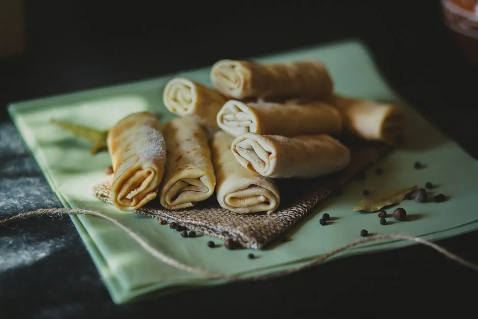 Delicious homemade crepes filled with spices, served on woven fabric, perfect for savory snacking.