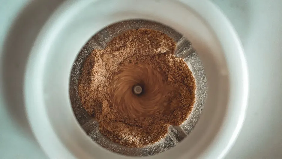 Top view of coffee beans grinding in a coffee grinder with visible swirling motion.