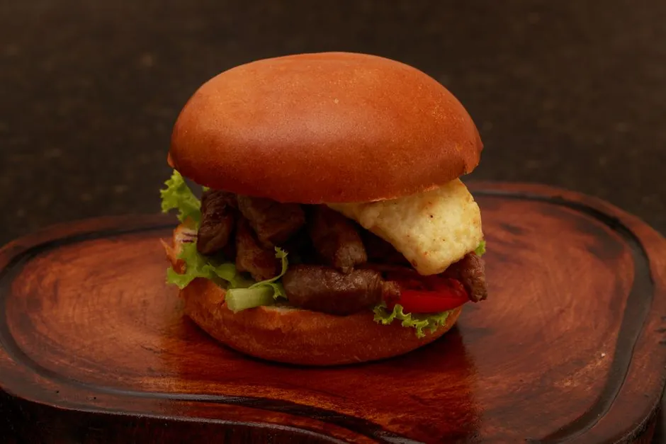 Close-up of a tasty gourmet burger with fresh ingredients on a wooden plate, perfect for food lovers.