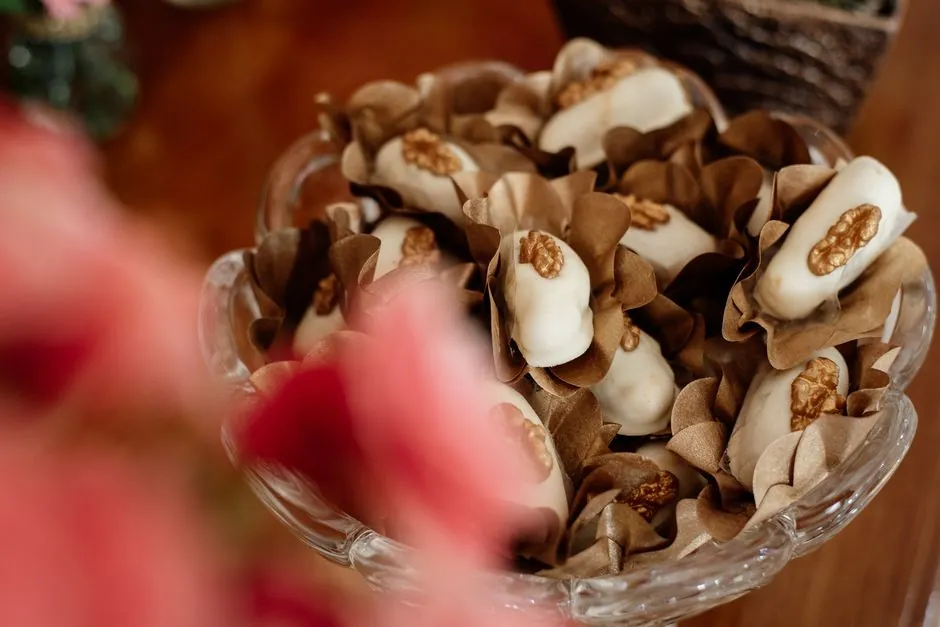 A collection of indulgent white chocolate desserts garnished with walnuts, beautifully presented in a glass dish.