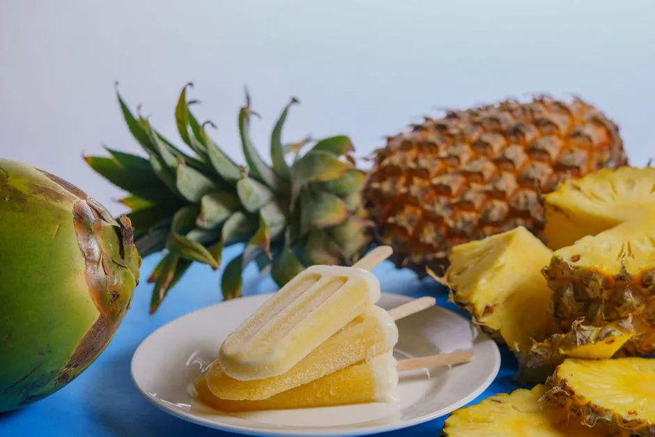 Refreshing tropical popsicles on a plate with coconut and pineapple slices.