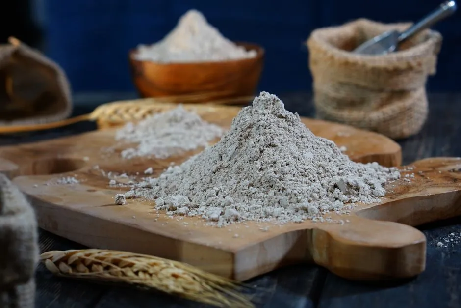 Close-up of flour on a wooden board with scattered grains for baking moods.
