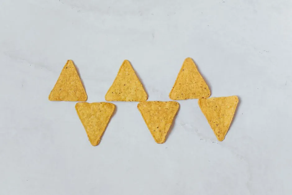 Flat lay of six tortilla chips arranged on a white background, perfect for snack and food themes.