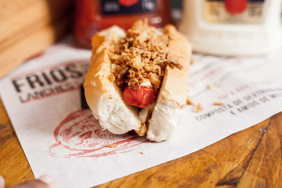 Close-up of a gourmet hot dog topped with crispy onions, showcasing a vibrant and appetizing presentation.