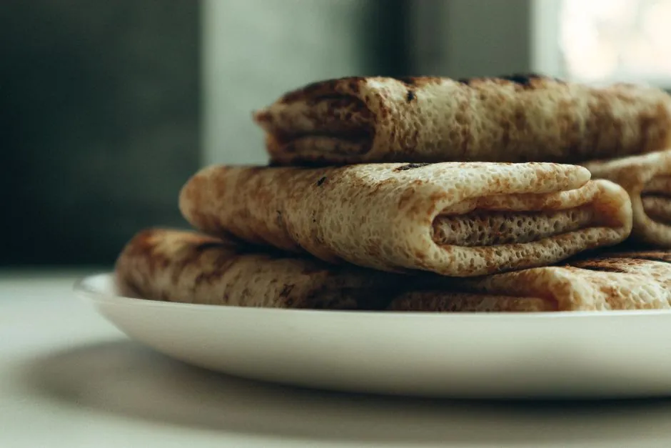 Delicious rolled pancakes neatly stacked on a white plate, ready to serve.