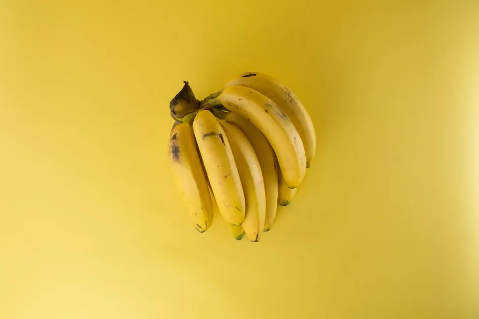 A vibrant bunch of ripe bananas on a matching yellow background, evoking freshness.