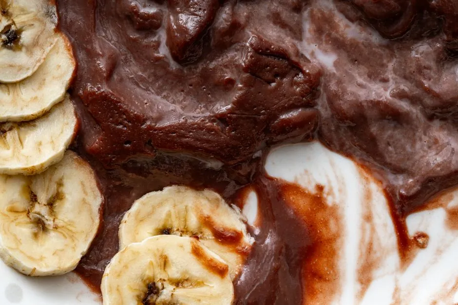 Close-up of banana slices with rich chocolate spread on a white plate, highlighting textures and contrast.