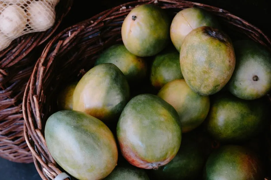 A close-up view of fresh mangoes in a rustic woven basket, highlighting their natural appeal.
