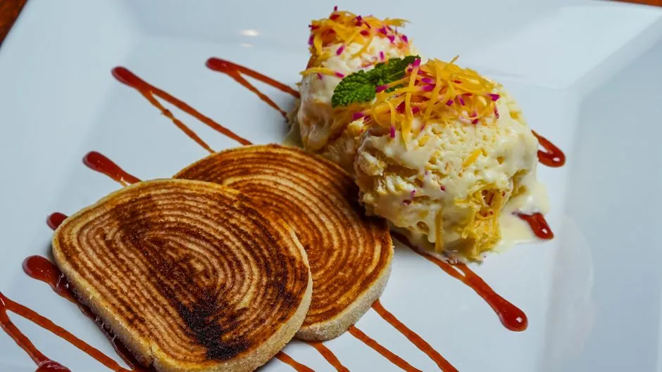 A deliciously presented gourmet dessert with ice cream, swirl toast, and decorative sauce.
