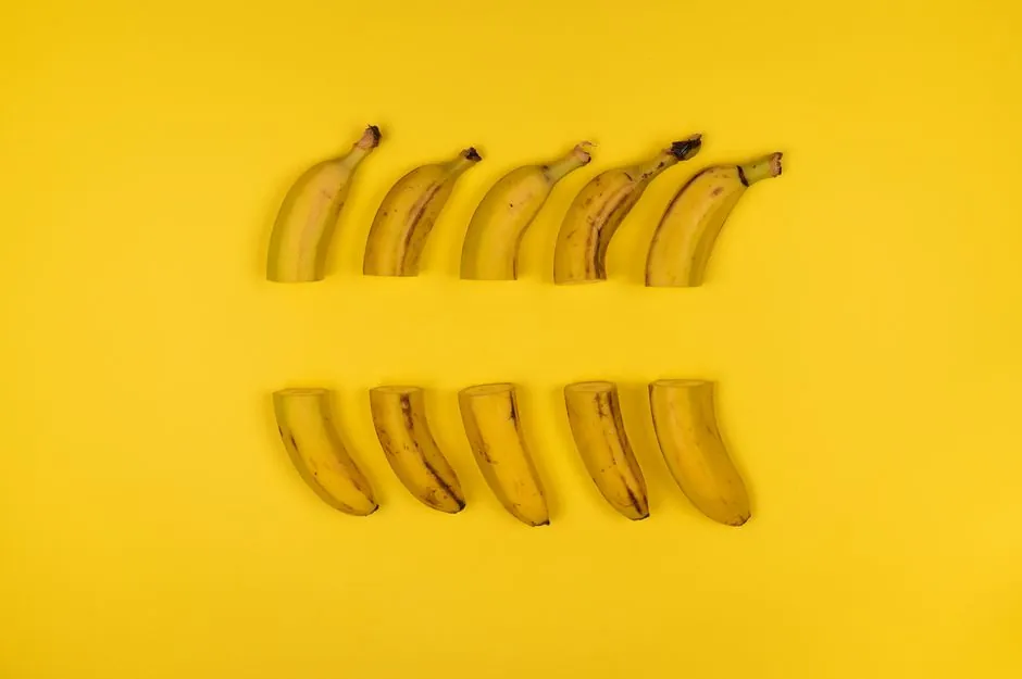 Creative composition of sliced bananas arranged on a vivid yellow surface.