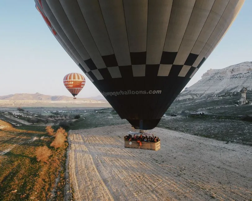 Aerial view of hot air balloons soaring over the scenic Cappadocia landscape during the day.