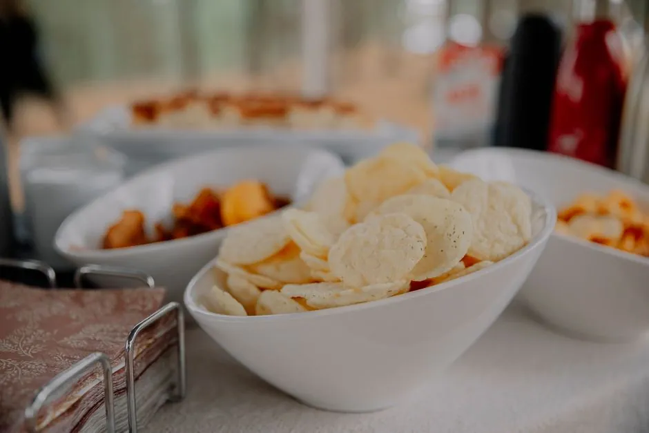 A variety of chips served in white bowls on a table, perfect for party snacks.